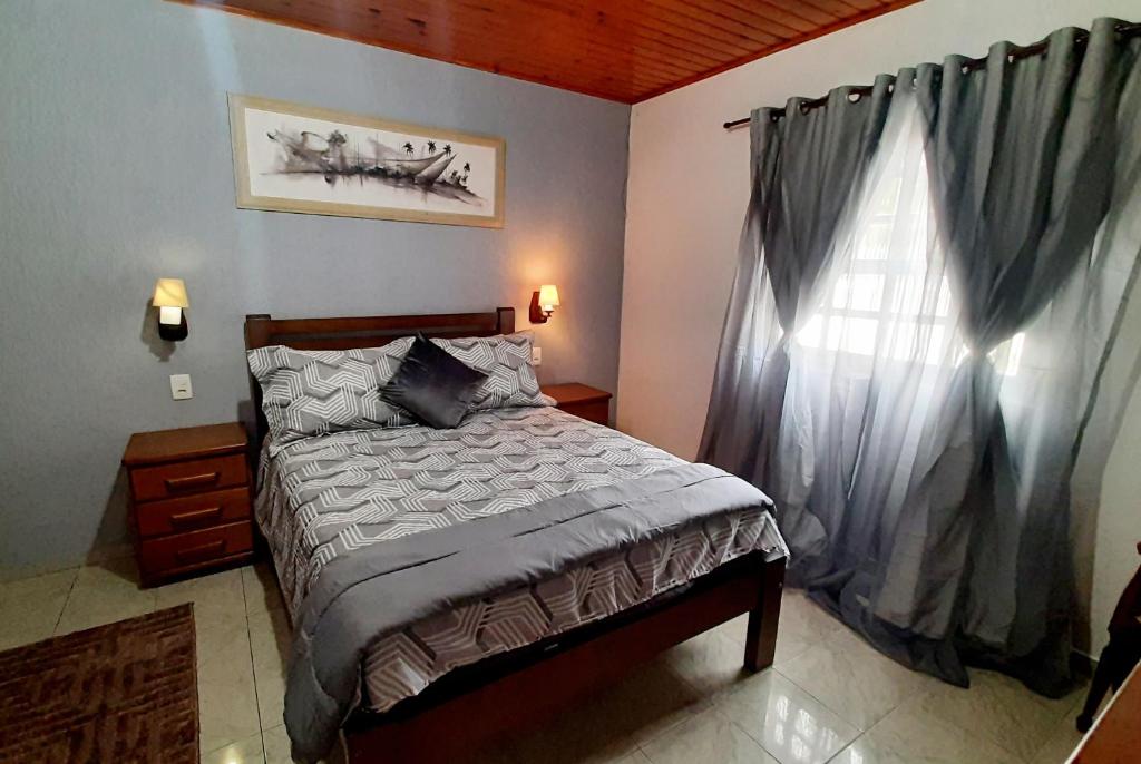 1 dormitorio con cama y ventana en Casa Campos do Jordão, en Campos do Jordão