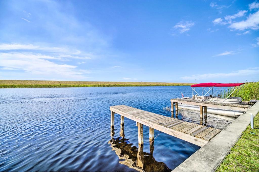 un muelle con una sombrilla roja sobre un cuerpo de agua en Cozy Cabin Rental in Waterfront Community with Dock en Okeechobee