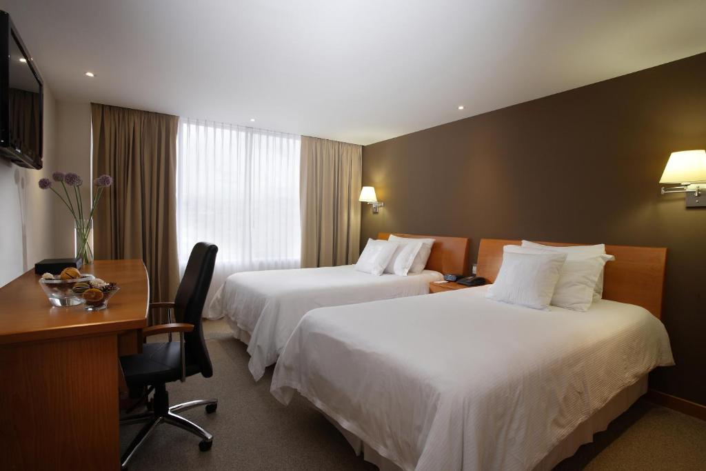 a hotel room with two beds and a desk at El Dorado Hotel in Cuenca