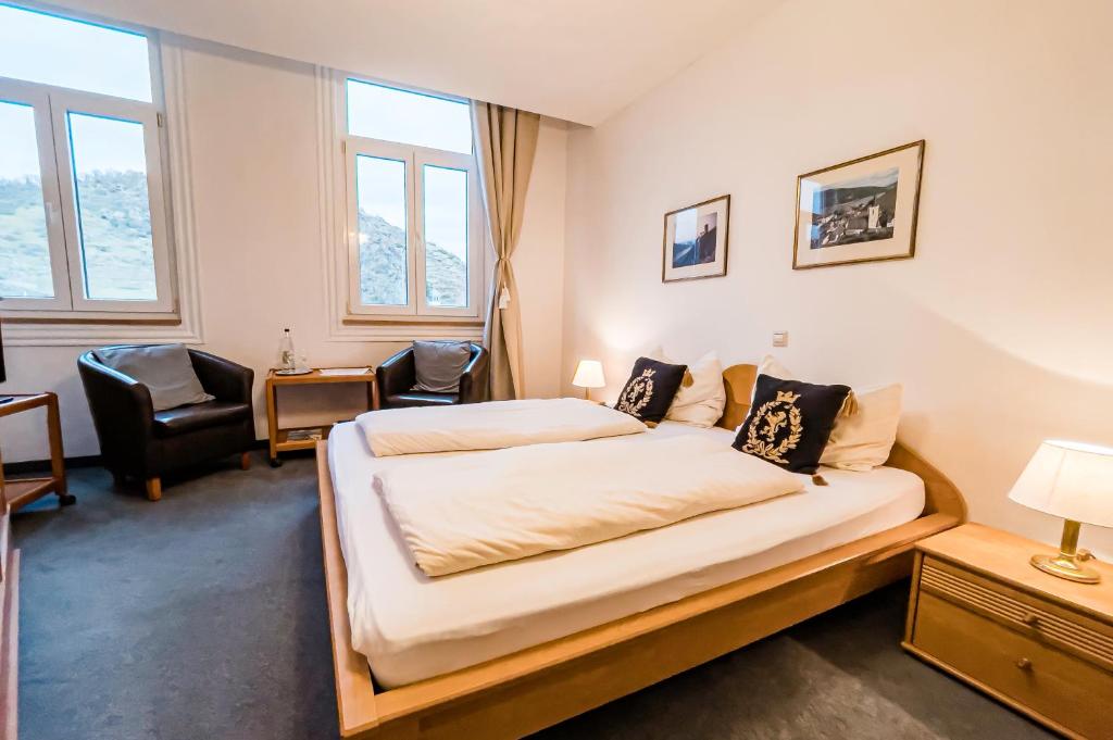 um quarto com uma cama grande num quarto com janelas em Hotel zum Goldenen Löwen em Sankt Goar