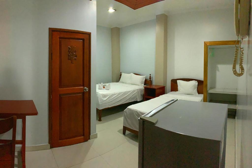 a hotel room with two beds and a door at Hostal Ventura Isabel in Iquitos