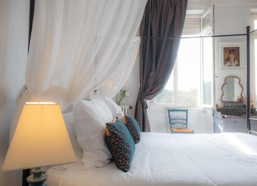 um quarto com uma cama branca com um candeeiro e uma janela em Villa Hortebise em Salies-de-Béarn