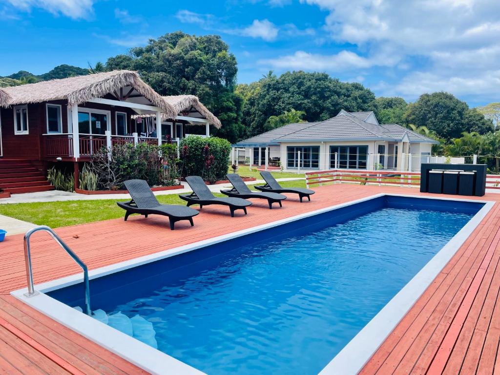a swimming pool with chairs and a house at Red Hibiscus Villas in Rarotonga