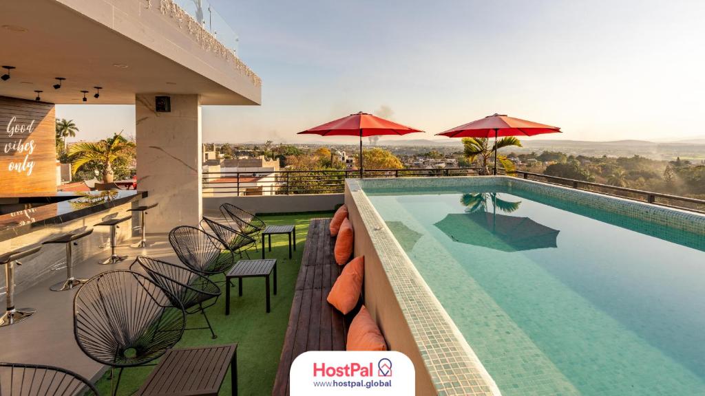 una piscina de hotel con mesas, sillas y sombrillas en Sierra Apartments- Estudios Oaxtepec, en Oaxtepec