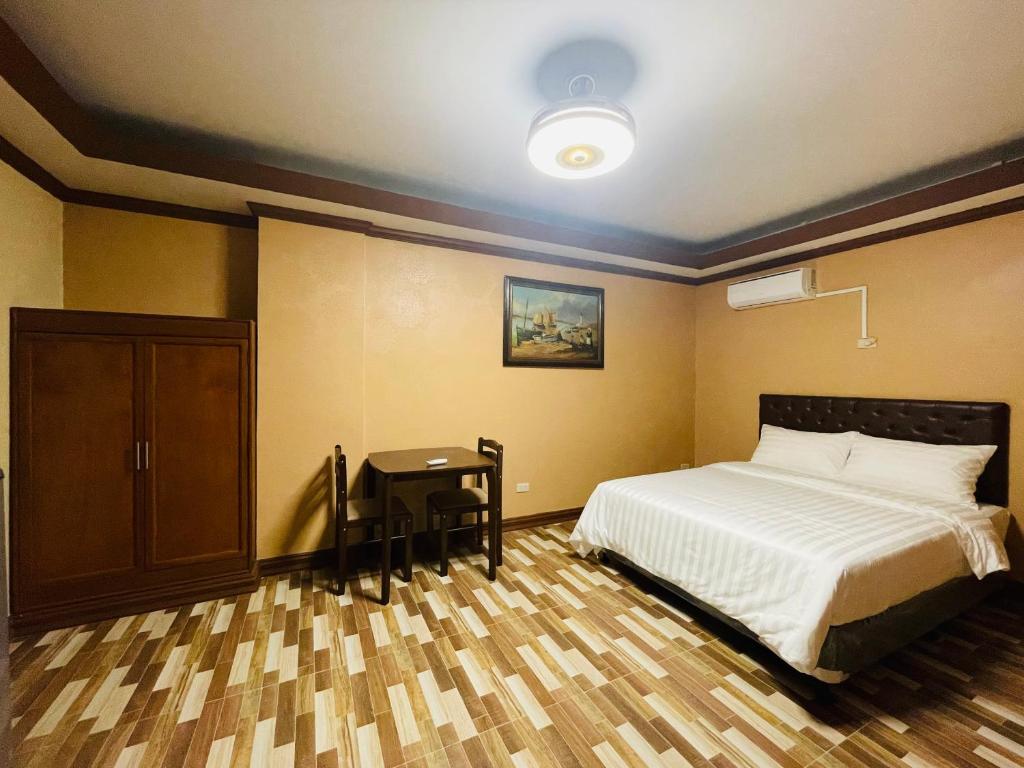 Un dormitorio con una cama y una mesa. en Drake Hotel Angeles City, en Ángeles