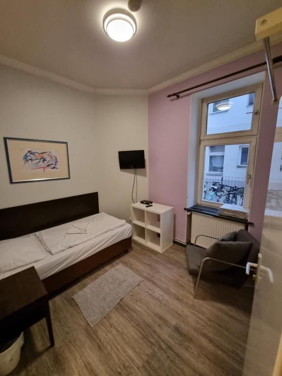 Un dormitorio con una cama y una silla y una ventana. en Albert rooms, en Berlín