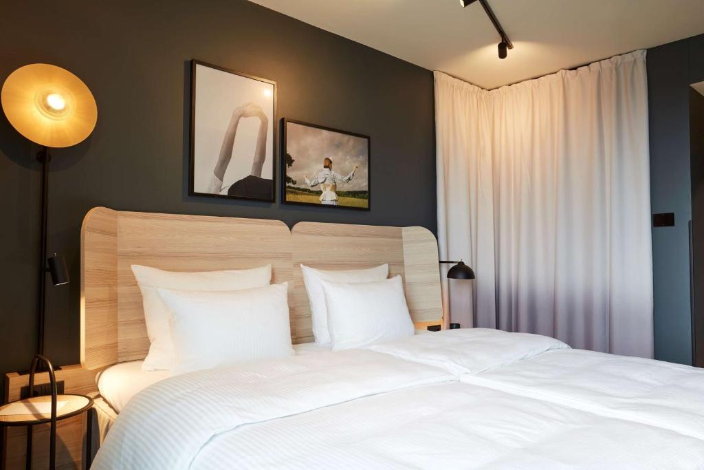 - une chambre avec un grand lit blanc et des oreillers blancs dans l'établissement Scandic Frankfurt Hafenpark, à Francfort-sur-le-Main