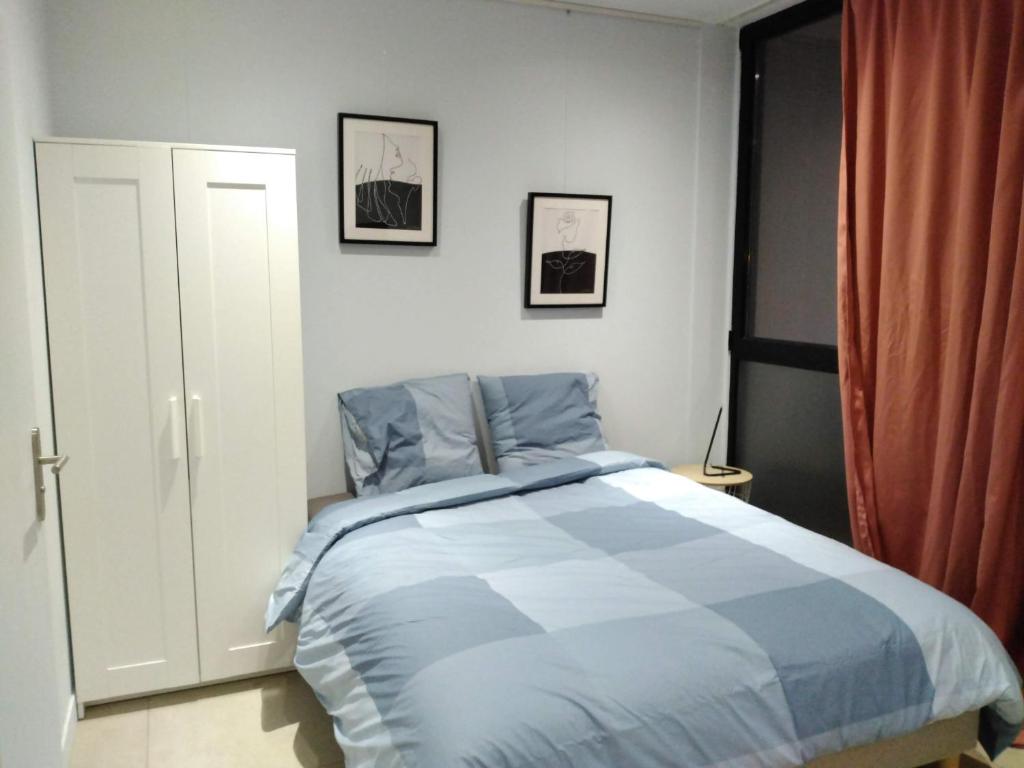 Schlafzimmer mit einem Bett mit blauer und weißer Bettwäsche in der Unterkunft Métal studio in Cachan