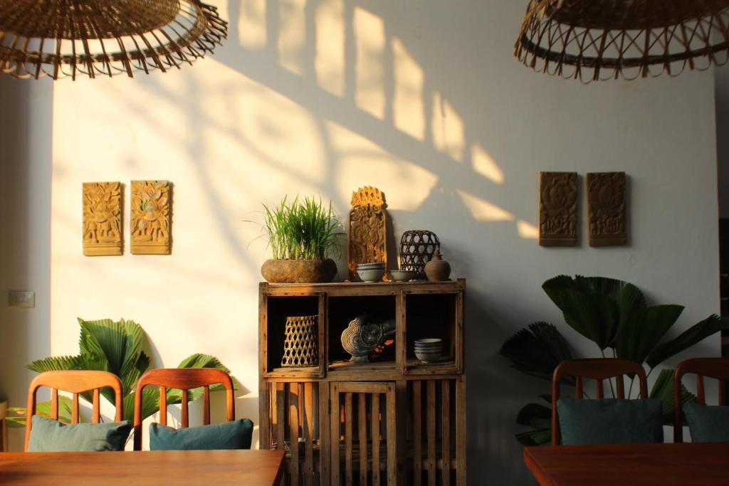 a dining room with a table and chairs and shadows on the wall at Nhà Lúa Homestay in Ninh Binh