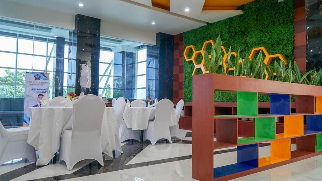 ein Esszimmer mit Tischen und Stühlen und einer farbenfrohen Wand in der Unterkunft Lombok Vaganza Hotel in Mataram