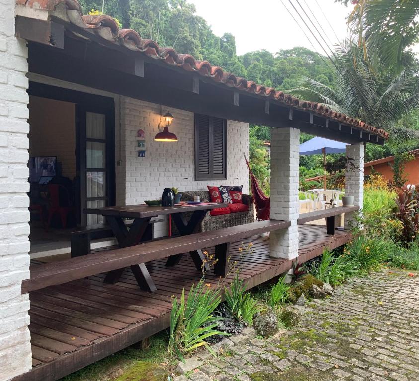 Casa da Baía في انغرا دوس ريس: سطح خشبي خارج منزل مع مقعد