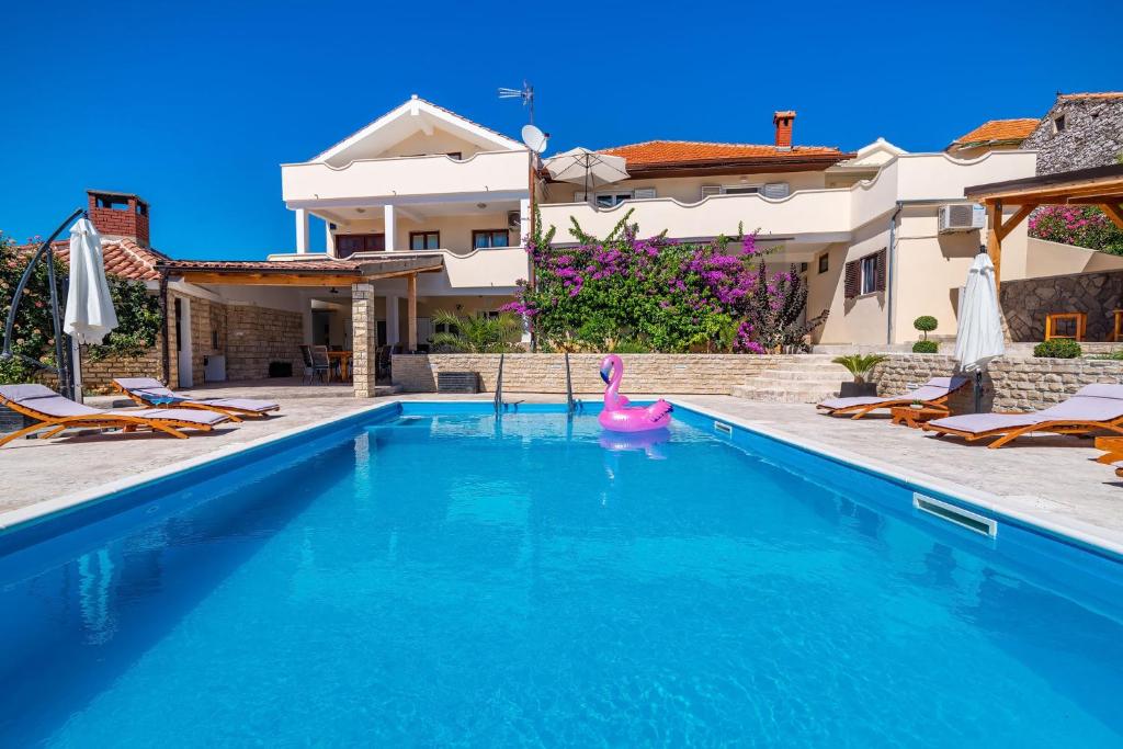 - une piscine avec un canard en caoutchouc rose en face d'une maison dans l'établissement Family-friendly apartments with swimming pool Sveti Filip i Jakov, Biograd - 20861, à Sveti Filip i Jakov