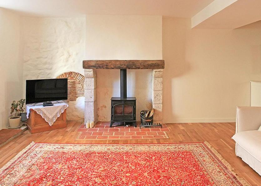 a living room with a fireplace with a tv and a couch at Maison de LOlivier, Beautiful Townhouse with Private courtyard in Eymet