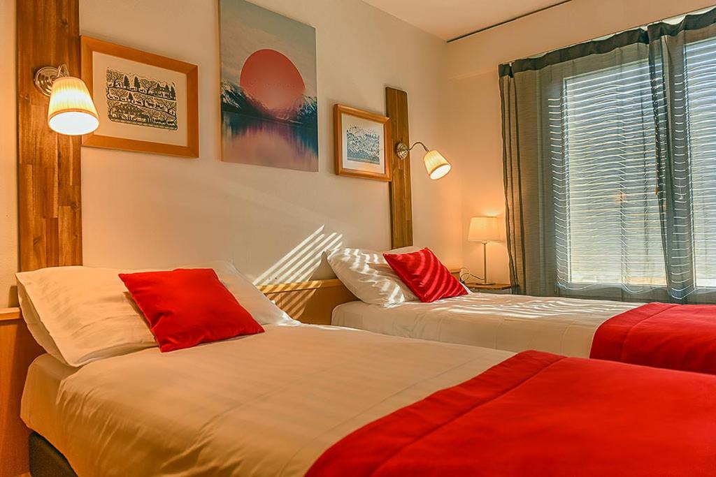 two beds in a room with red and white at Hotel des Alpes Bulle center in Bulle