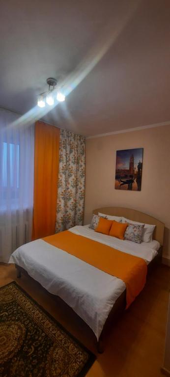 ein Schlafzimmer mit einem großen Bett mit einer orangefarbenen Decke in der Unterkunft 2ком квартира у Набережной в Астане in Astana