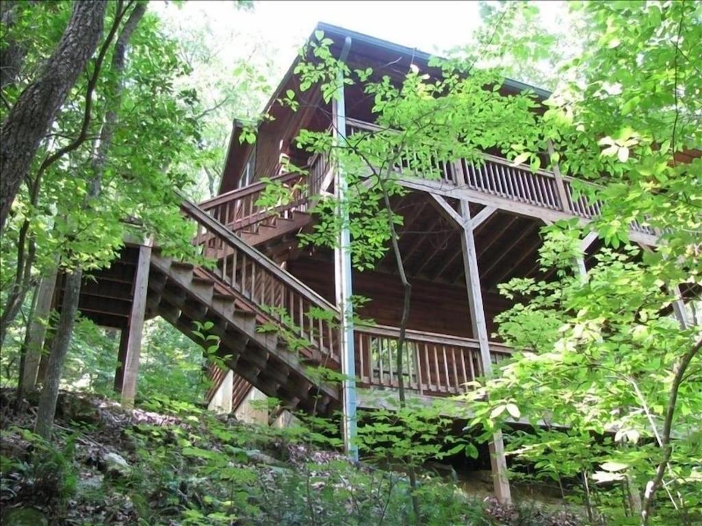 uma casa na árvore no bosque com uma escada em Alpenhaus Cabins Real Log Home in Helen Ga Mountains with hot tub and balconies em Sautee Nacoochee