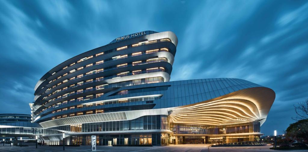 ein Bürogebäude mit geschwungener Fassade in der Dämmerung in der Unterkunft Primus Hotel Shanghai Hongqiao in Shanghai