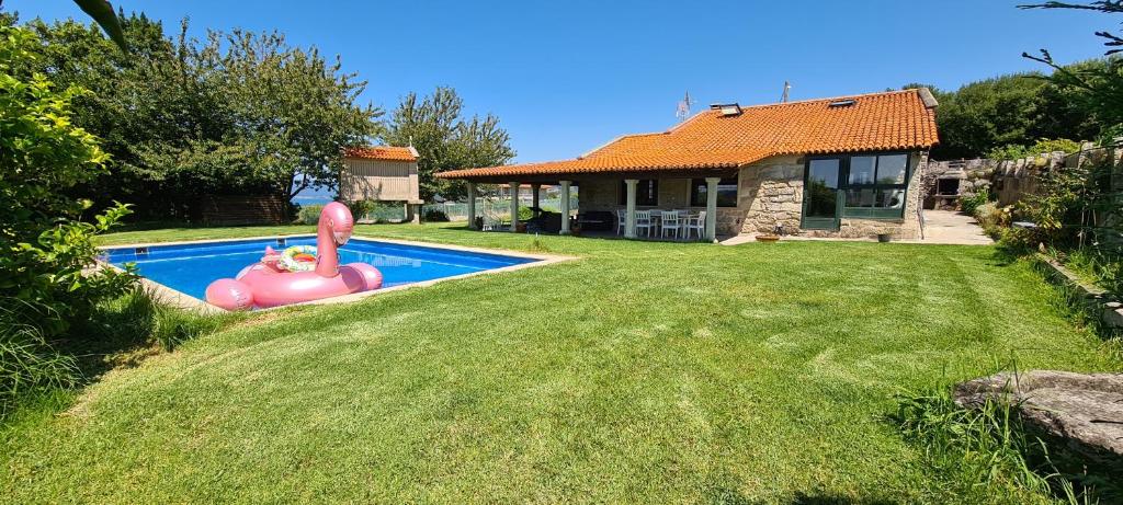 a backyard with a pool with a inflatable pig in the yard at Eira Vella Bueu in Bueu