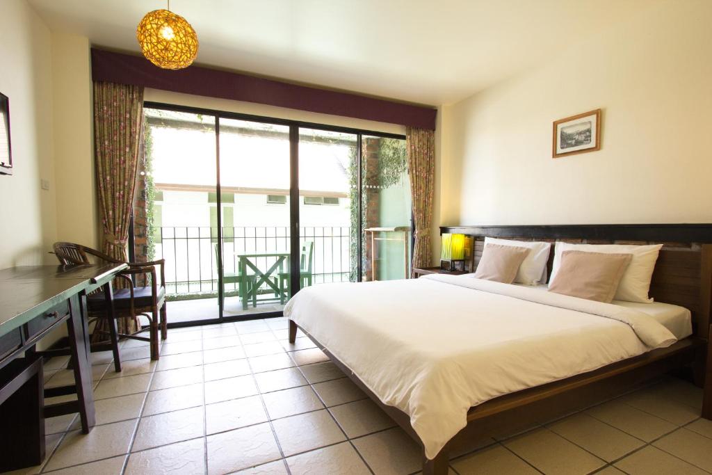 a bedroom with a large bed and a balcony at Khaolak Tony Lodge in Khao Lak