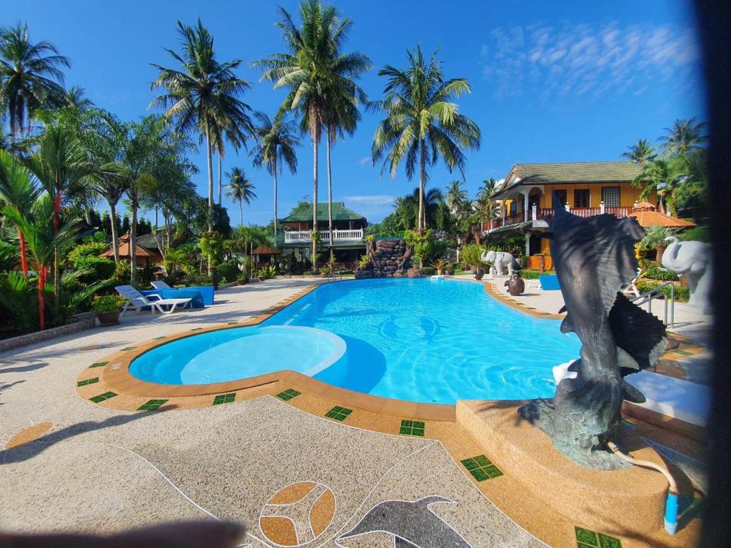 a swimming pool in front of a house with palm trees at Jungle Village Bungalow in Ao Nang Beach
