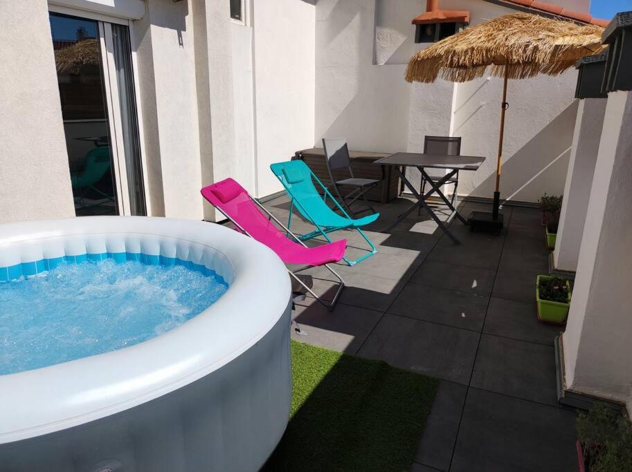 a hot tub on a patio with chairs and a table at Studio terrasse 27m2 RESERVATION SUR RBNB in Perpignan