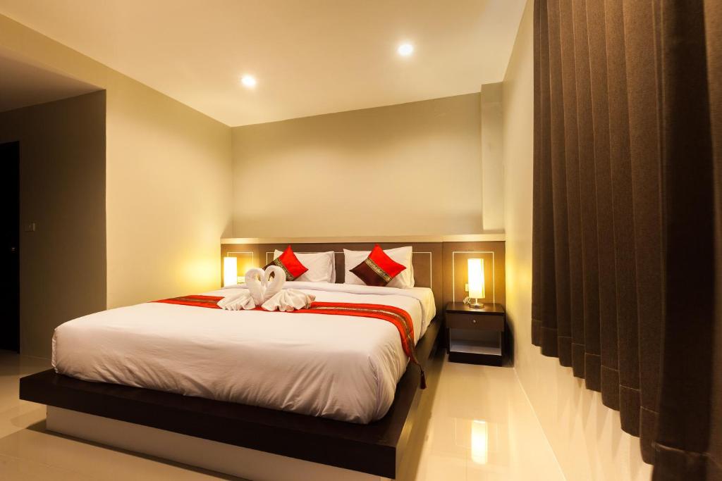 ein Schlafzimmer mit einem großen weißen Bett mit roten Kissen in der Unterkunft Pranee Home Phang-nga in Ban Khaek