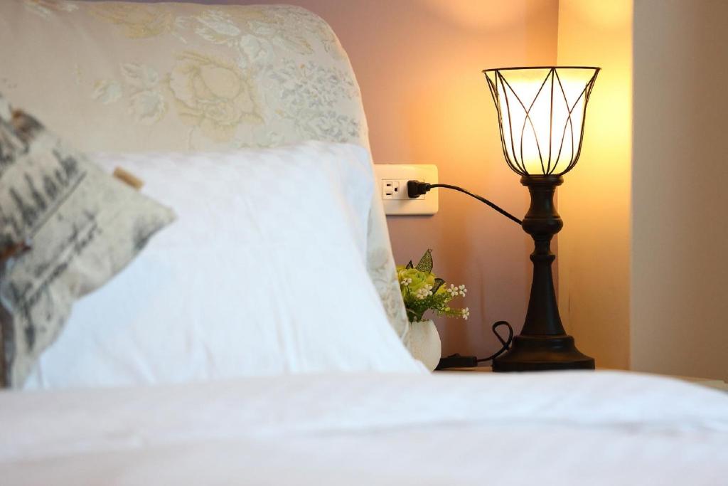 a bedroom with a white bed with a lamp at Dear B&amp;B in Hualien City