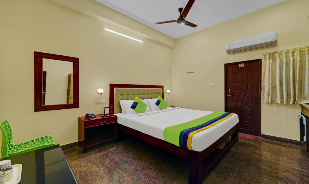 1 dormitorio con cama, silla y espejo en Treebo Trend Grace Inn 3 Min Walk From Promenade Beach, en Pondicherry