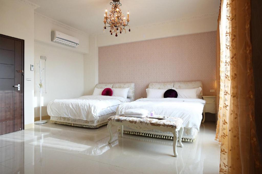 a bedroom with two beds and a chandelier at Dear B&amp;B in Hualien City