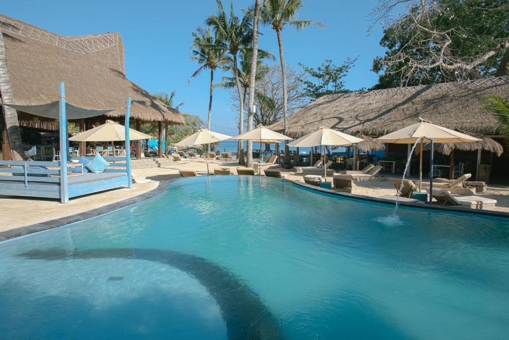 uma grande piscina com guarda-sóis e cadeiras em Le Nusa Beach Club em Nusa Lembongan