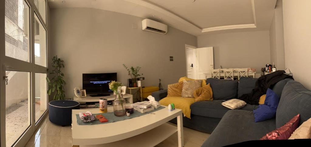 a living room with a blue couch and a tv at AlReem Apartment in Al Madinah