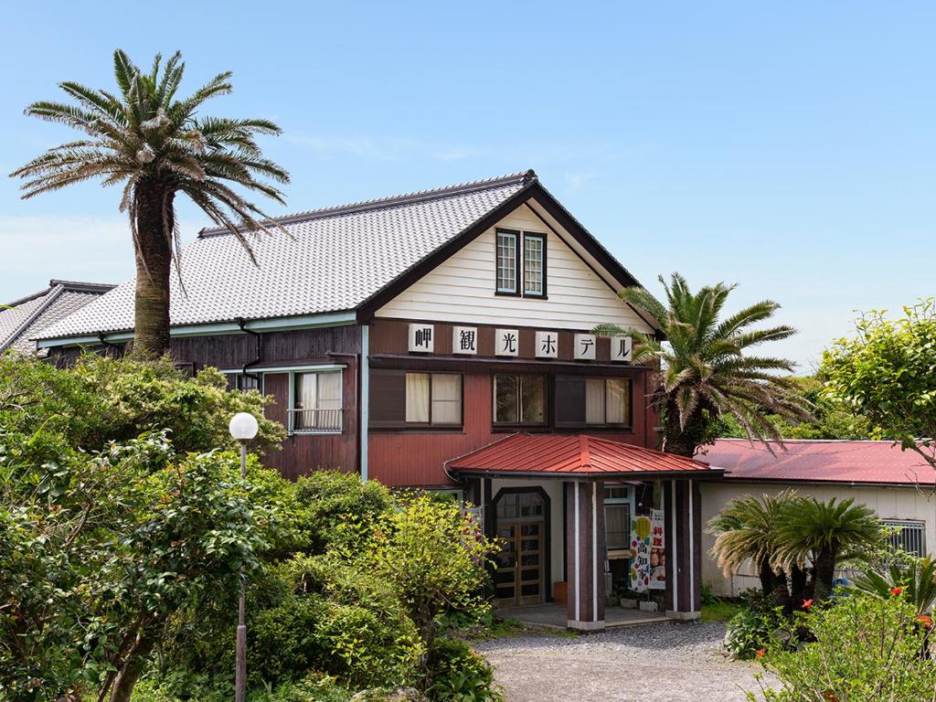 une maison rouge avec des palmiers devant elle dans l'établissement Misaki Kanko Hotel, à Muroto