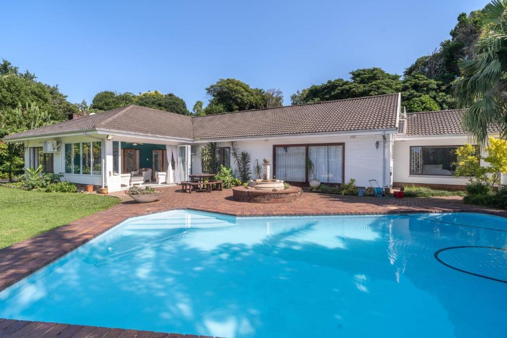 een zwembad voor een huis bij Spacious retreat with large pool and lush garden in Pinetown