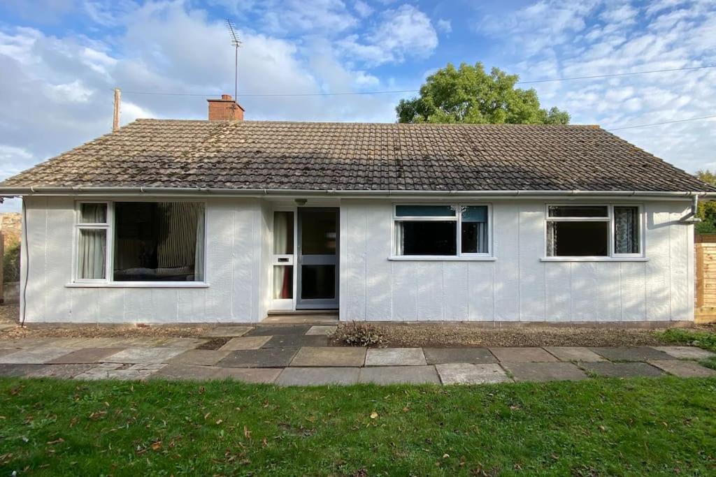 a white house with a roof at Cheerful 3 bedroom bungalow with indoor fire place in Gloucester