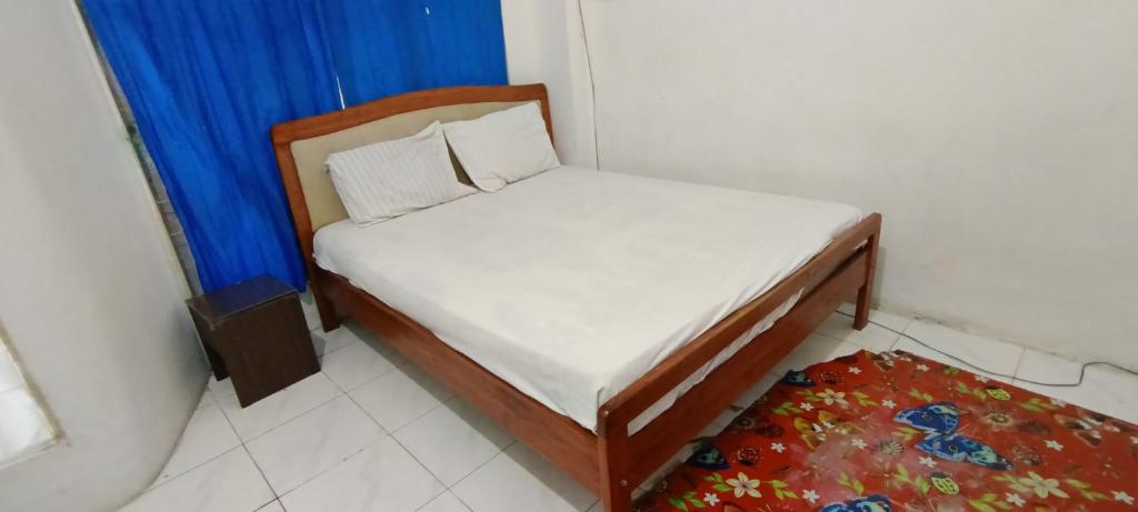 ein kleines Bett in einem Zimmer mit einem blauen Vorhang in der Unterkunft SPOT ON 92338 Karin Kost in Banjarbaru