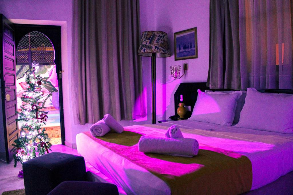 a bedroom with a large bed with pink lighting at Majorel Perle Hôtel Riad Restaurant Picine & Spa in Marrakesh