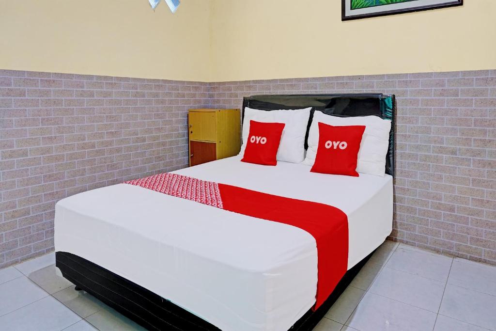 1 dormitorio con 1 cama con 2 almohadas rojas en OYO 92359 Kost Maluku 36 Family Residence, en Blitar