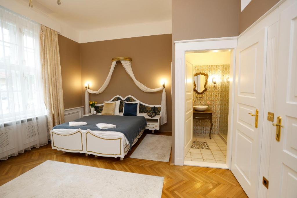 a bedroom with a king sized bed and a bathroom at Villabaroque_Eger in Eger