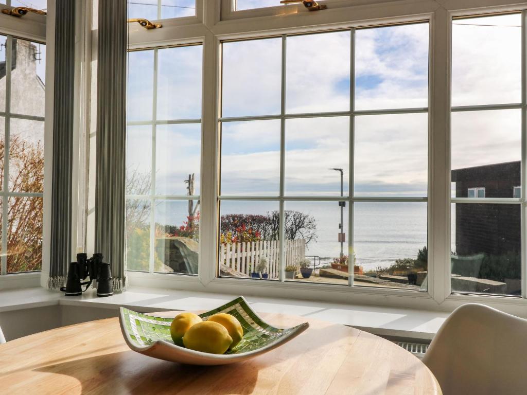 un bol de fruta en una mesa frente a una ventana en Beach Cottage, en Kinghorn