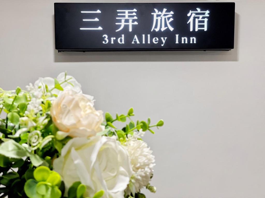 a sign on a wall with a bouquet of flowers at 三弄旅宿3rd Alley Inn in Kaohsiung