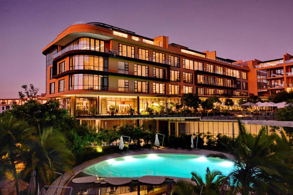 un hotel con piscina frente a un edificio en The Houghton Hotel, Spa, Wellness & Golf en Johannesburgo