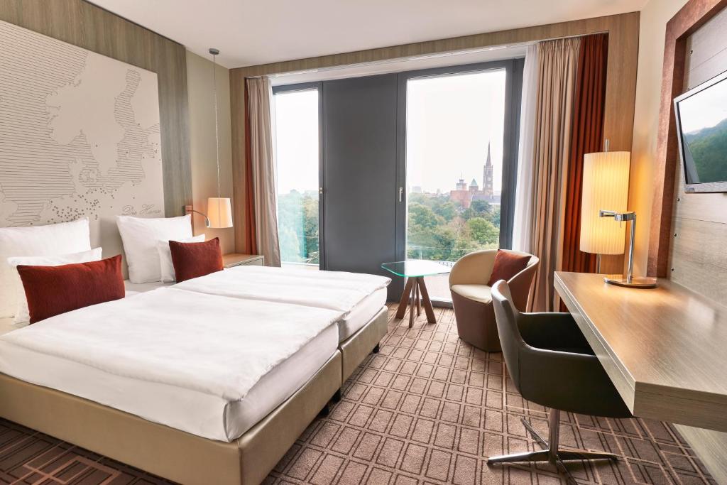 a hotel room with a bed and a large window at Steigenberger Hotel Bremen in Bremen