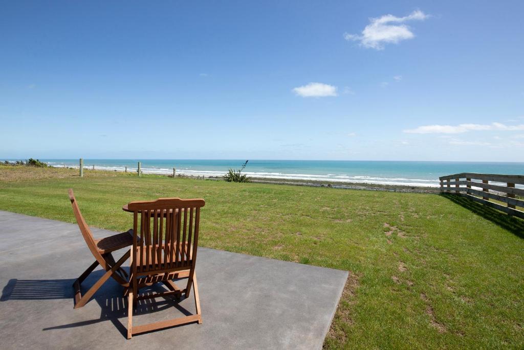 a wooden rocking chair sitting on a sidewalk near the beach at Views over Tasman, New luxury boutique studio overlooking the Tasman Sea in Greymouth