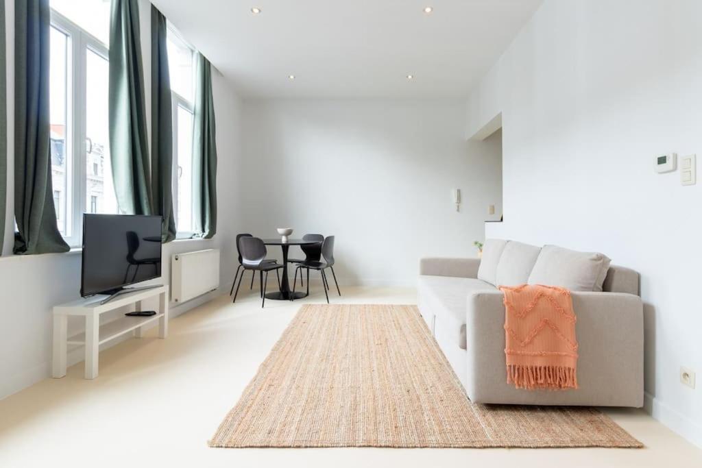 Il comprend un salon blanc doté d'un canapé et d'une télévision. dans l'établissement Lichtrijk appartement op toplocatie in Gent, à Gand