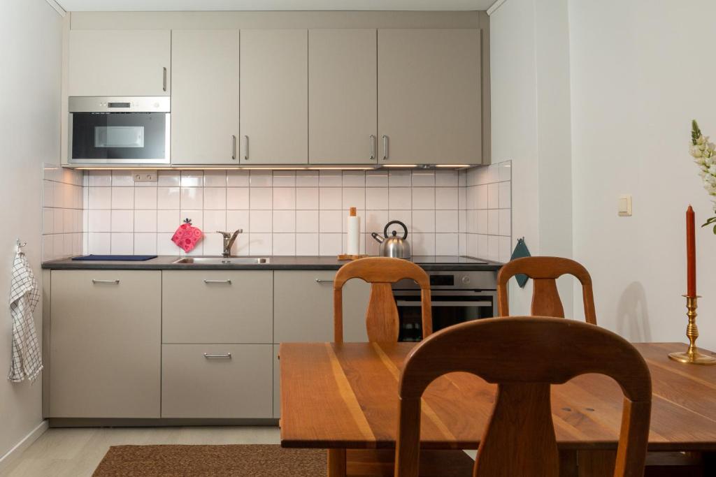 a kitchen with white cabinets and a wooden table and chairs at Blå Dörren in Höör