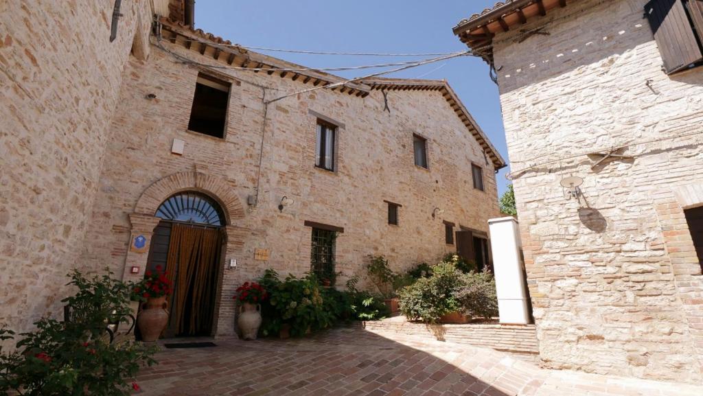 um antigo edifício de pedra com uma porta num pátio em Borgo de' Varano by Hotel I Duchi em Camerino