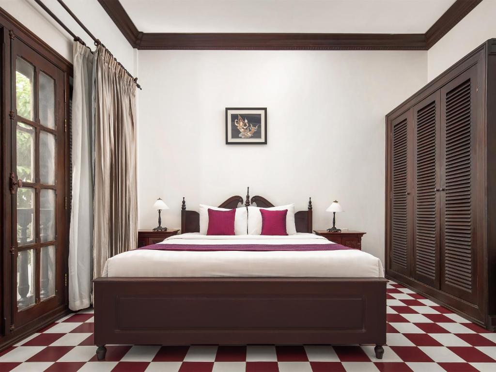 a bedroom with a bed with red and white checkered floors at Chateau d'Angkor La Residence in Siem Reap