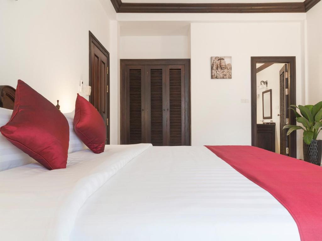 a bedroom with a large white bed with red pillows at Chateau d'Angkor La Residence in Siem Reap
