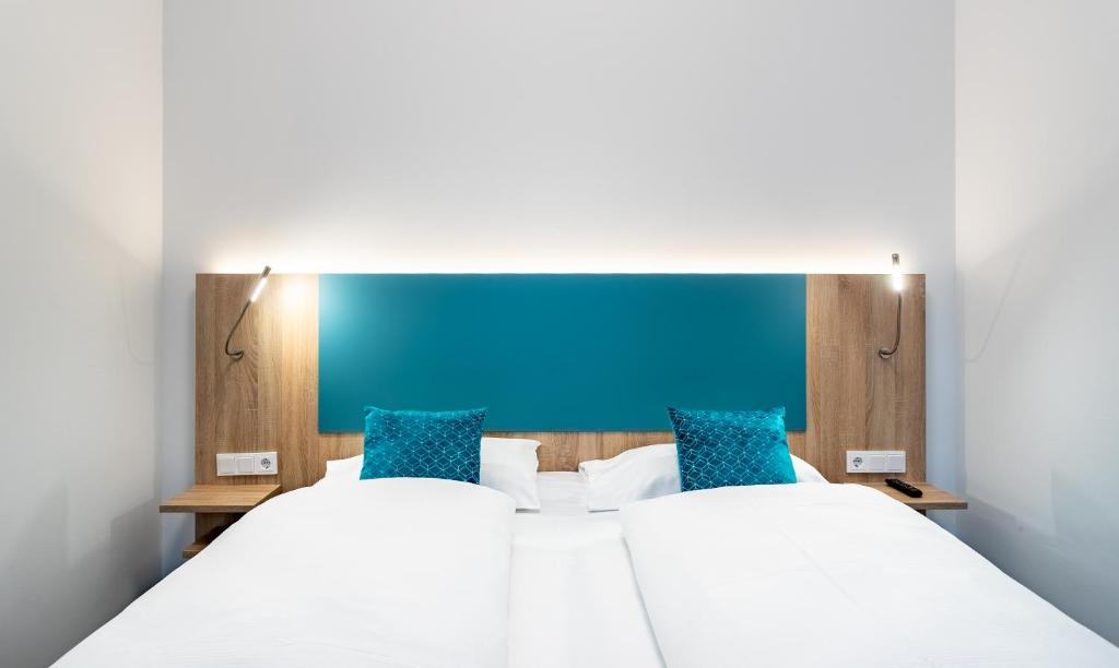 a bedroom with two beds and a blue headboard at DaunTown Rooms - Self Check-In in Vienna