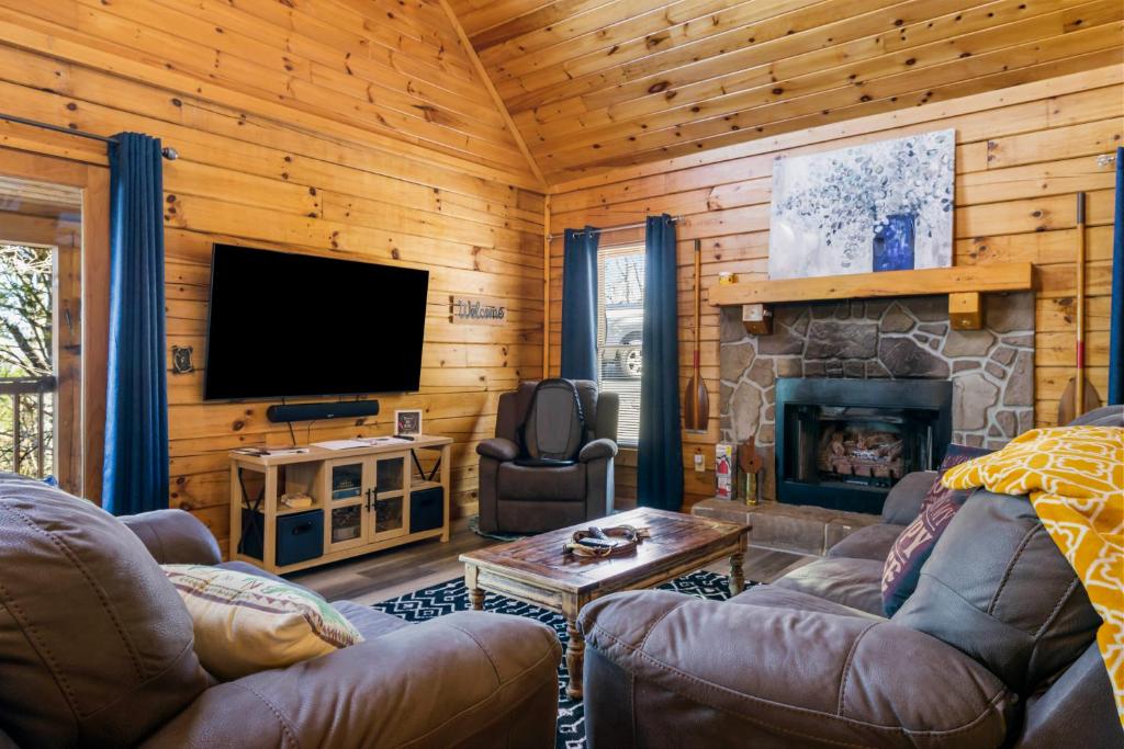 uma sala de estar com televisão e lareira em Serenity, A Rustic Log Cabin Retreat em Sevierville